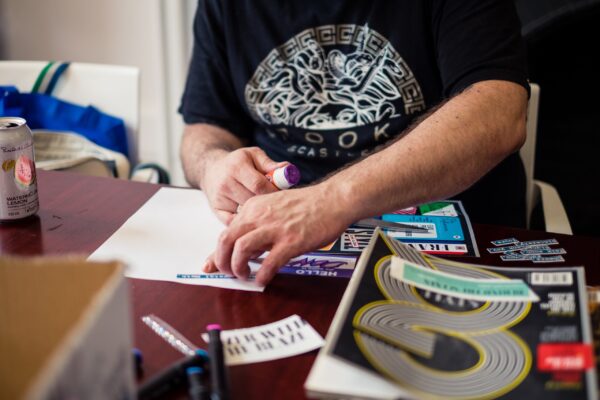 Someone's hands while they paste words cut from magazines on a white paper.